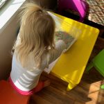 A little girl is finding M items in a sensory bin full of rice.