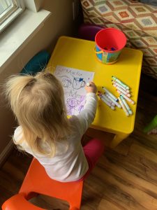 A little girl is coloring a picture of items that start with the letter M.