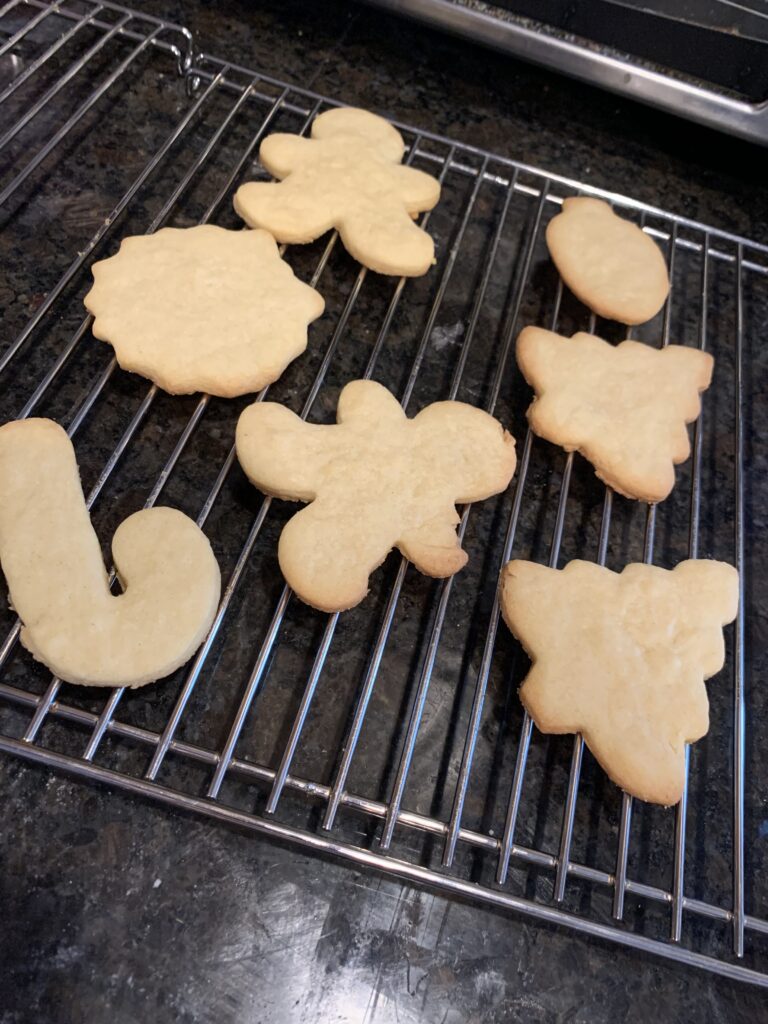 7 Christmas cookies are cooling off on a wire rack.