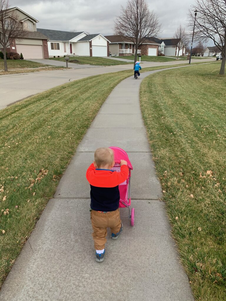 Toddler enjoying nature play during a neighborhood walk with family.