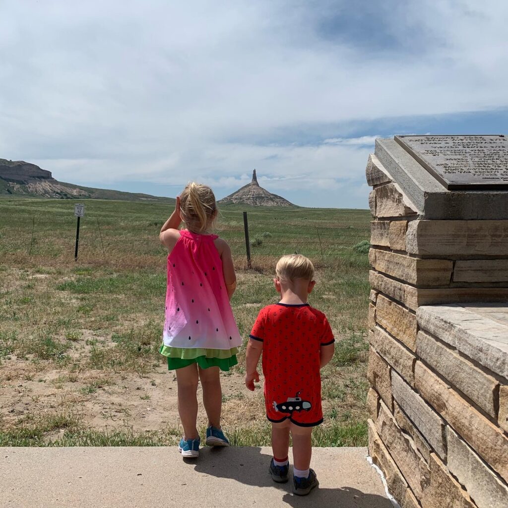 Children enjoying nature play while observing a unique rock formation during a family outing.