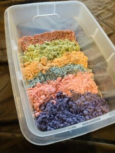 This is a bin full of homemade moon sand. The sand is colored from top to bottom: red, green, orange, blue, pink, and purple. This is to represent Joseph's coat of many colors.