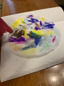 A child is spraying a colored coffee filter on a paper towel.