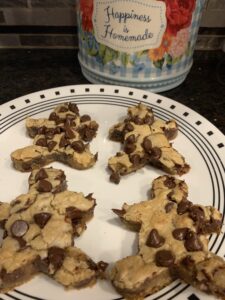Leprosy Cookies This image has a plate of 4 chocolate chip cookies that are cut to the shape of gingerbread men. Behind the plate, there is a cookie jar that says, "Happiness is Homemade."