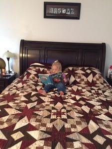 Young child sitting on a bed and looking through a picture book during quiet time for kids.